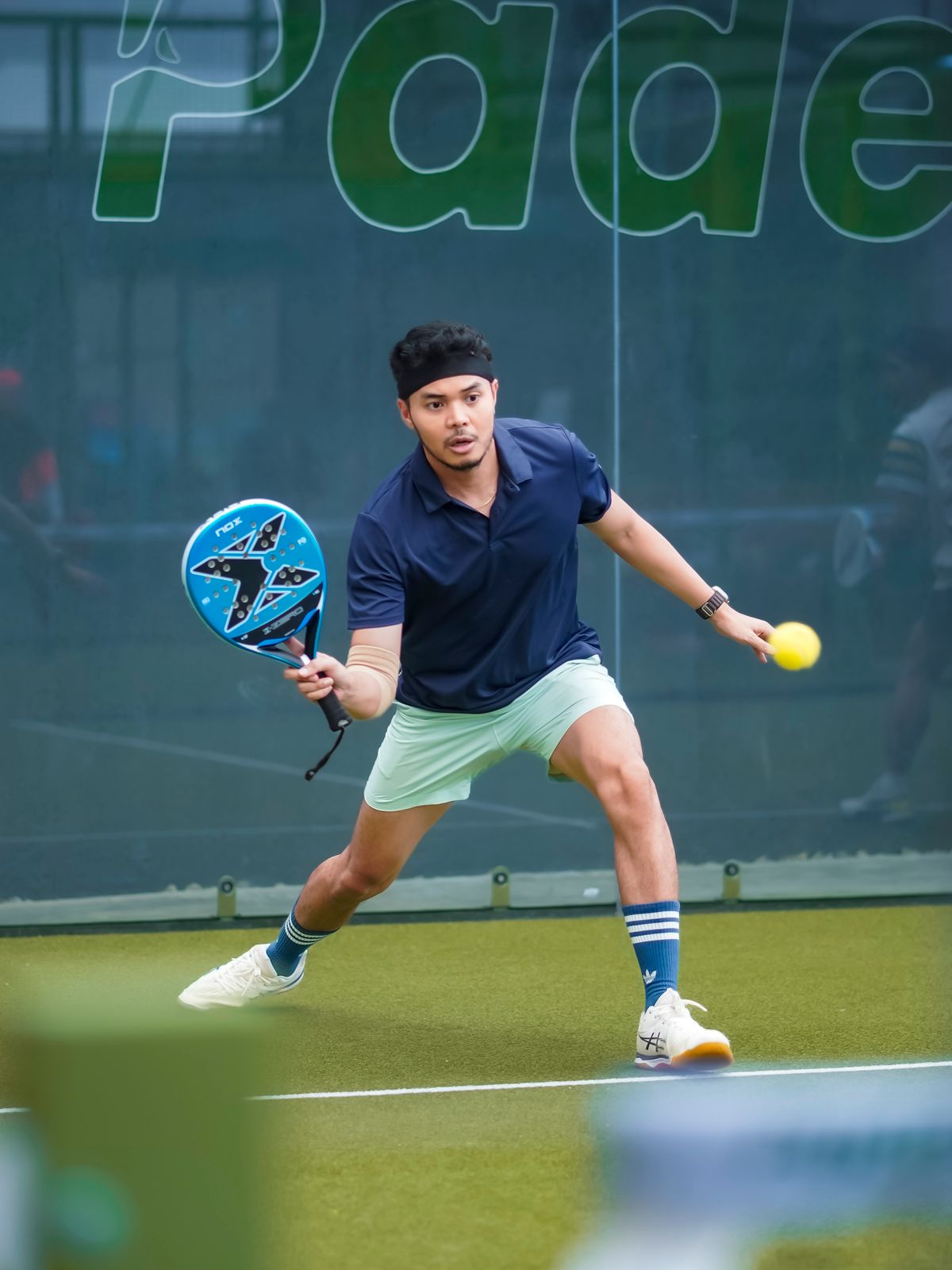 Pemain padel melakukan pukulan forehand di lapangan Padel Co., Bandung