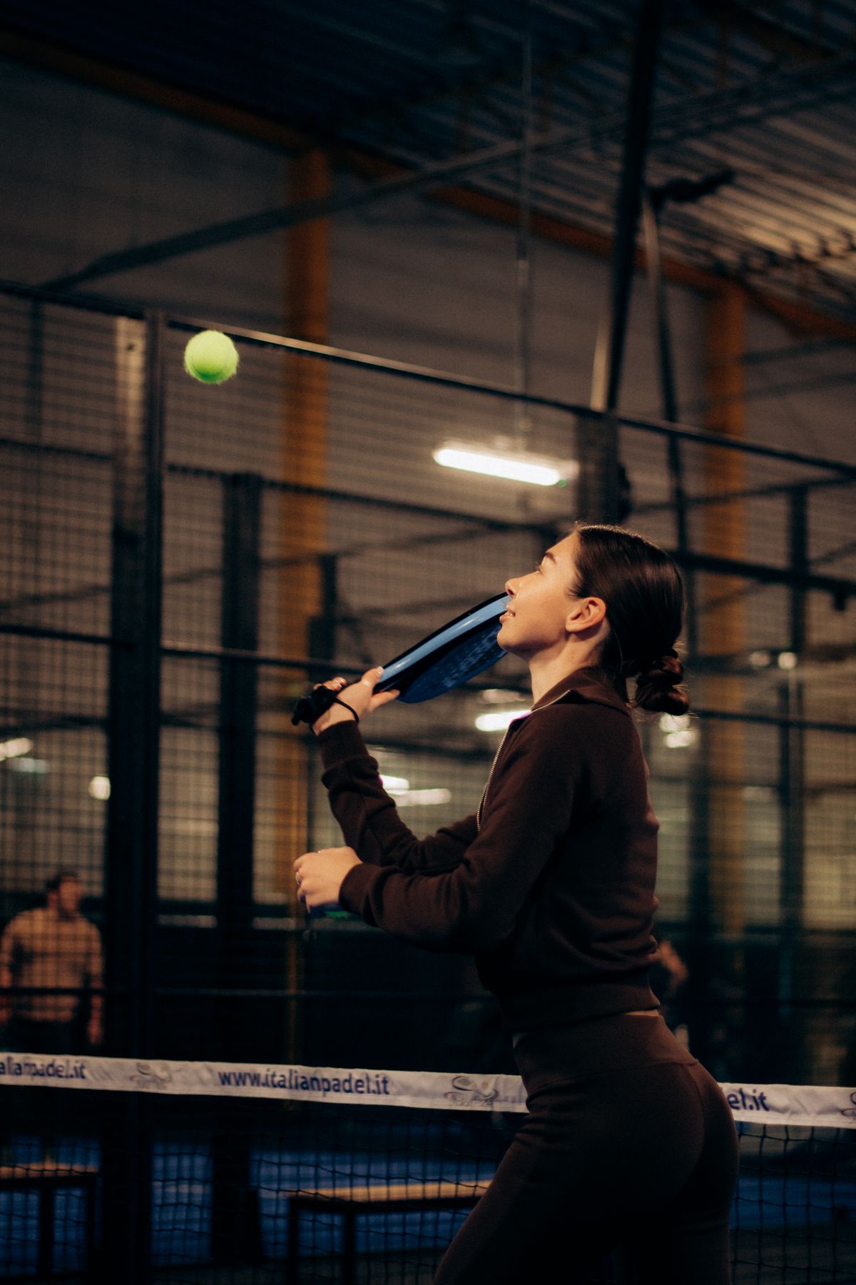 Pemain padel melakukan smash di lapangan semi outdoor Padel Co.
